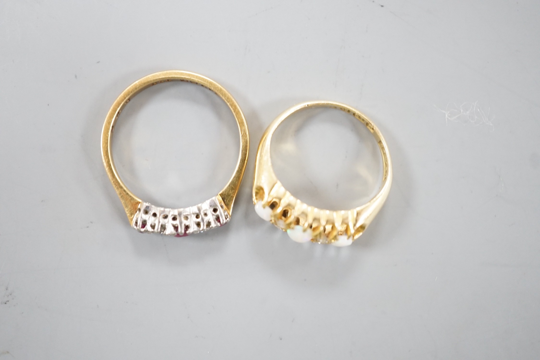 An Edwardian 18ct gold and three stone white opal set ring, with diamond chip spacers, size F and an 18ct and plat, three stone ruby and two stone diamond set ring, size M, gross weight 5.7 grams.